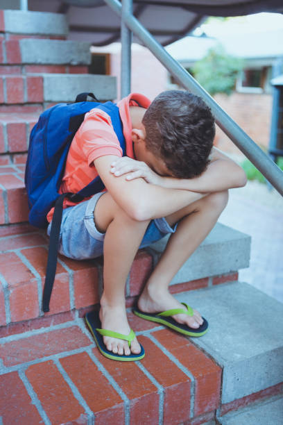 istock Sad schoolboy sitting alone on staircase 653912888
