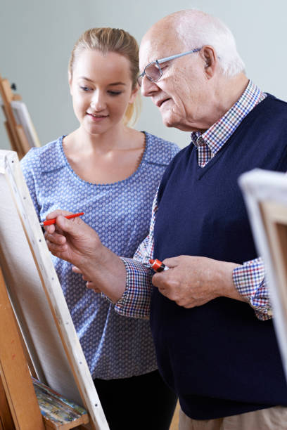 istock Senior Man Attending Painting Class With Teacher 653914300