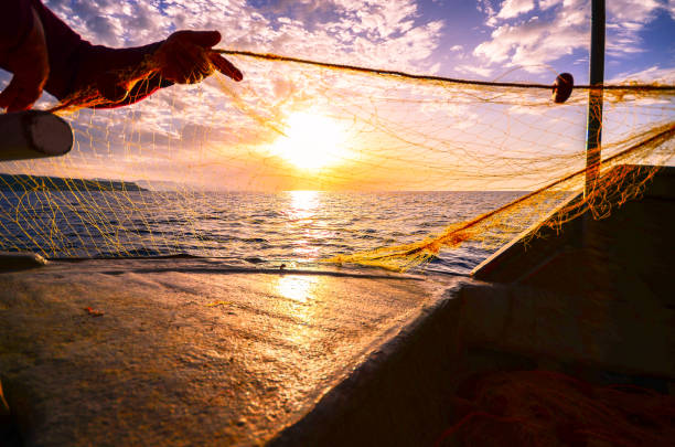 Fisherman's hand silhouette  throwing fishing net at sunset, Crete, Greece