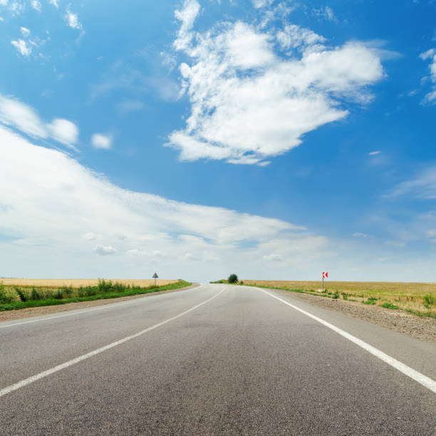 istock asphalt road to horizon and blue sky with clouds over it 653924368