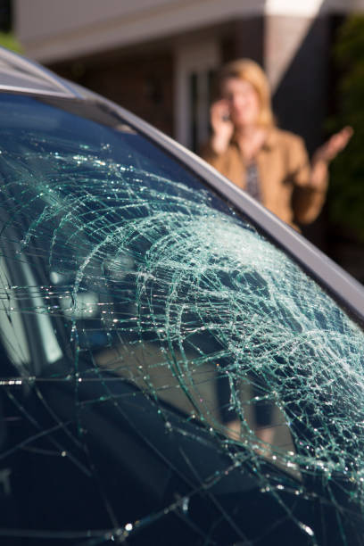 mulher telefonando para ajuda depois que quebrou o para-brisa do carro - broken window glass women - fotografias e filmes do acervo