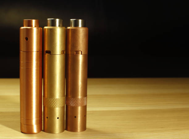 istock Three brass and copper mechanical mods for vaping (electronic cigarette) on the wooden surface on black background close up 653930218