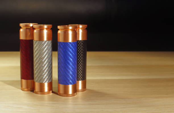 istock Four multicolored (red, blue, white and black) mechanical mods for vaping (electronic cigarette) on the wooden surface on black background close up 653930242