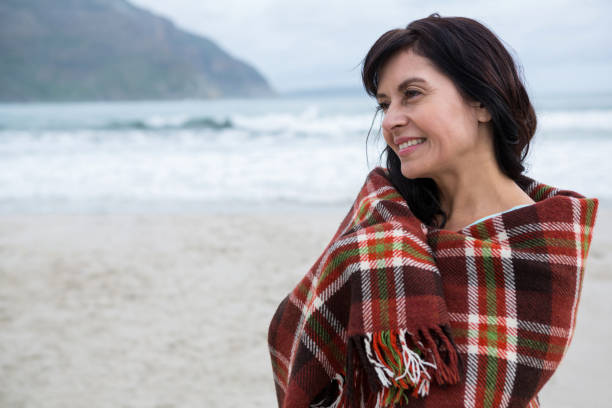 istock Happy woman wrapped in shawl on beach 653932304