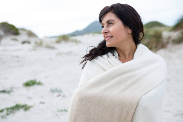 istock Thoughtful woman wrapped in shawl on beach 653932442