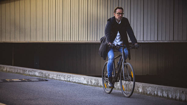 istock Mid adult man riding bicycle in an urban environment 653933698