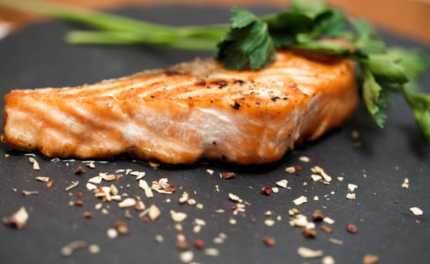 istock Grilled salmon and spices on black volcanic Board 653936390