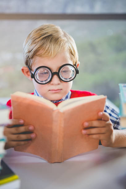 istock Close-up of schoolkid reading book in classroom 653940108