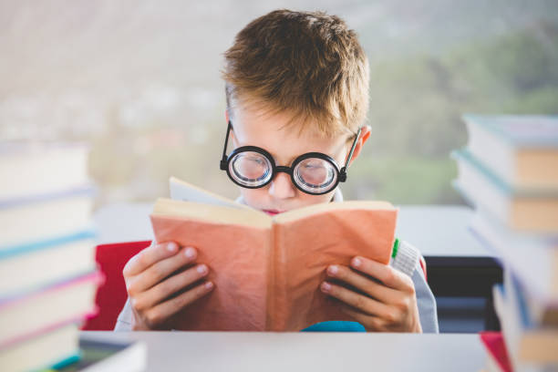 istock Close-up of schoolkid reading book in classroom 653940458