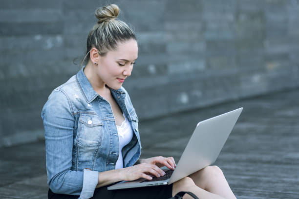 istock Woman using laptop on the street 653943628
