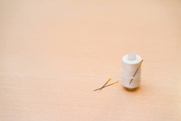 istock a spool of white thread with needle in the background. 653947628