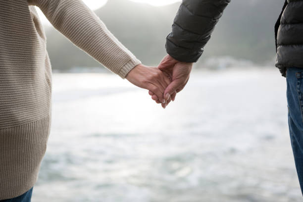 istock Mid section of couple holding hands on beach 653950598