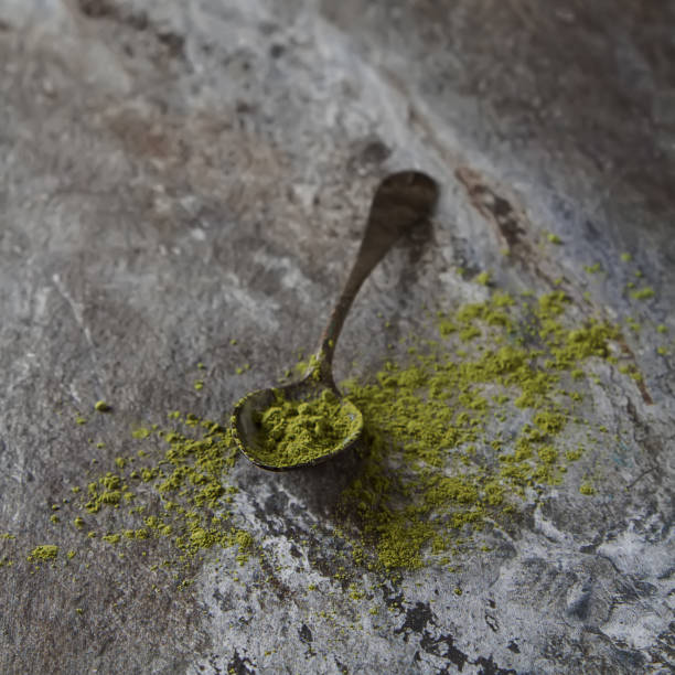 Matcha tea on an old vintage spoon. Gray background.