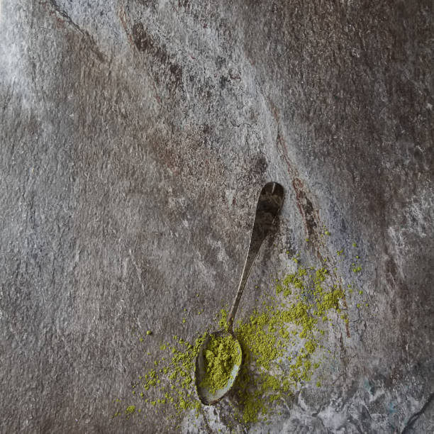 Matcha tea on an old vintage spoon. Gray background. Top view
