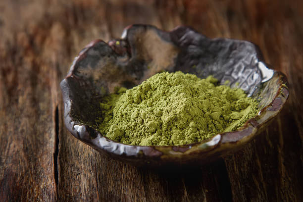 istock Dry Matcha tea in a small brown plate. Dark wood background 653950686