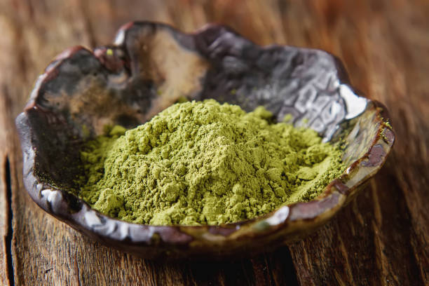 istock Dry Matcha tea in a small brown plate. Dark wood background 653950704