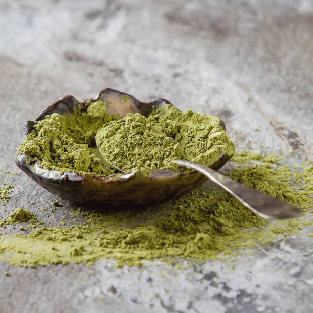 istock Dry Matcha tea in a small brown plate. Dark ceramic background 653950794