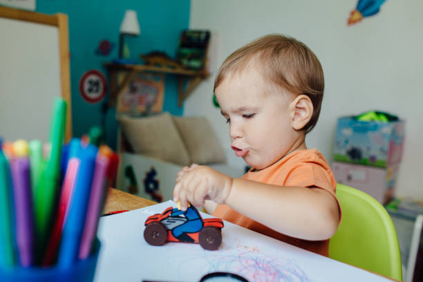 menino da criança brincando sozinho no quarto com uma moto de brinquedo - fine motor skills - fotografias e filmes do acervo