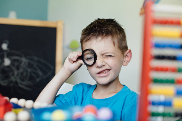 istock Schoolboy looking through a magnifying glass 653962978