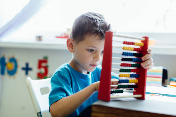 Thinking schoolboy learning maths with an abacus stock photo