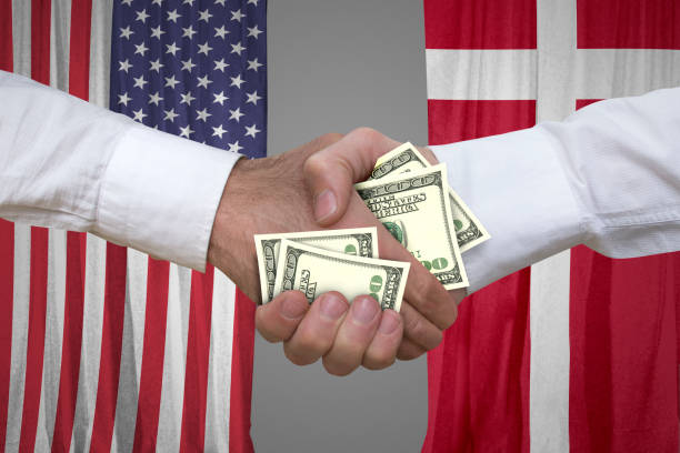 istock 100 dollar bills handshake with USA and Denmark's flags background. 653965164