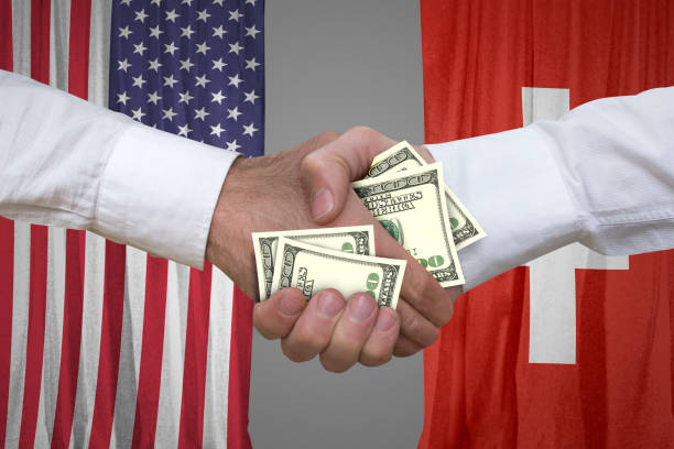 istock 100 dollar bills handshake with USA and Switzerland's flags background. 653965206