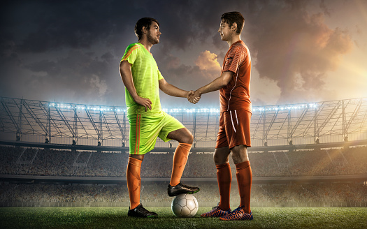 two soccer team captains on a soccer field shaking hands before the game