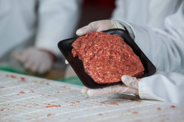 istock Butcher holding raw meat patties arranged in tray 653966824