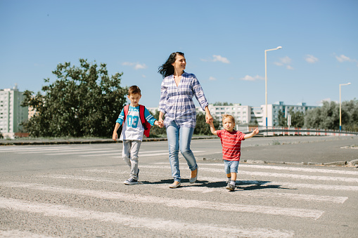 Madre y sus hijos cruzando un camino en el camino a la escuela en la mañana photo