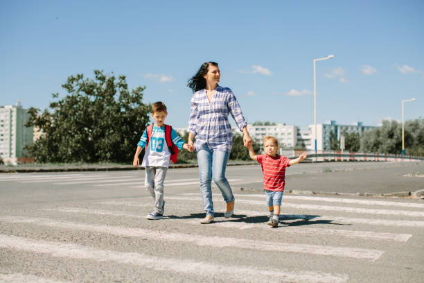 Mother and her children crossing a road on way to school in the morning stock photo