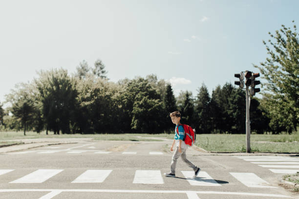 colegial cruzando un camino en su camino por la mañana a la escuela - crossing zebra crossing crosswalk street fotografías e imágenes de stock