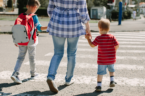 Imagen recortada de una madre cruzando una calle con sus hijos photo