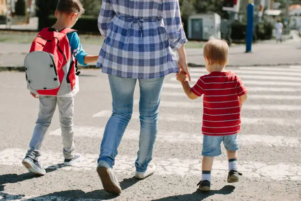 Photo of Cropped image of a mother crossing a road with her children