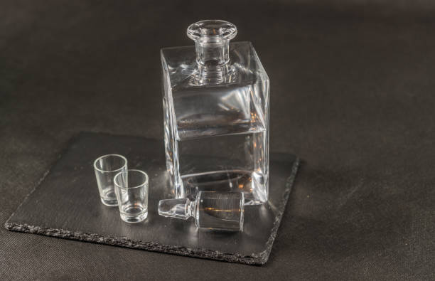 istock right side view on a pure vodka in crystal, modern carafe with a beautiful stopper and two glasses, the whole on a black stone plate 653968034