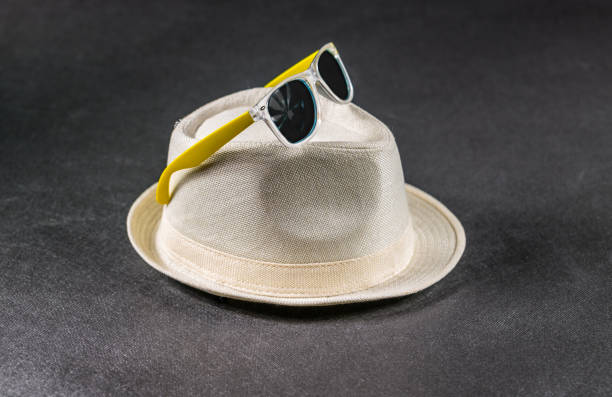 yellow sunglasses on white stylish hat, the whole on a black background, tropical set