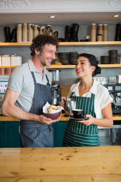 istock Waiter and waitress holding bowl with snack and coffee cup 653969878