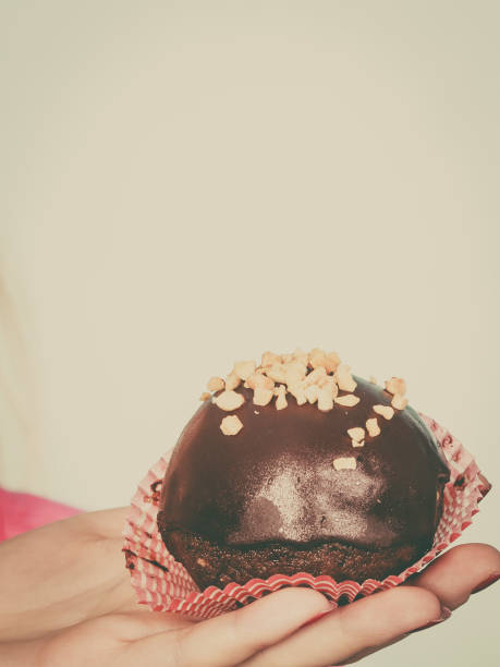 istock Woman hand holding chocolate cupcake about to bite 653969896