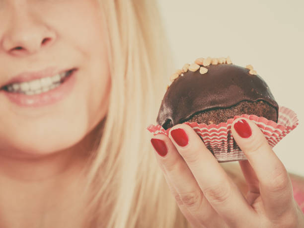 istock Woman holding chocolate cupcake about to bite 653971426