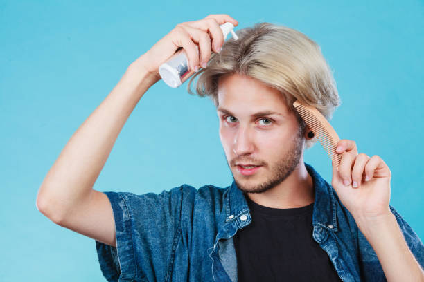 istock Man applying spray cosmetic to his hair 653971728
