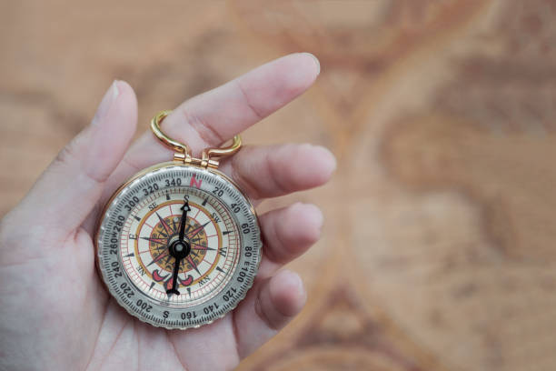 istock Golden compass in woman's hand with vintage world map background, travelling, exploring world concept 653972858