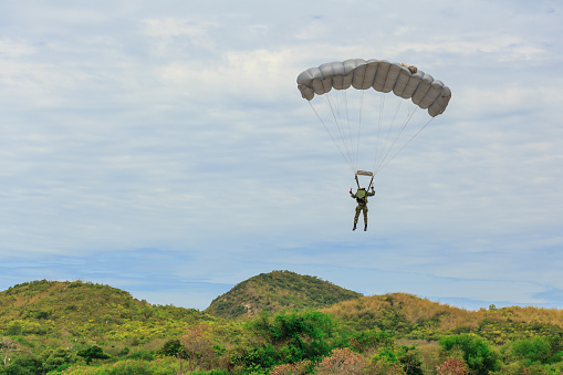 Paracaidista desciende y entrena en la precisión de aterrizaje que el paracaídas sobrevuelo sobre la montaña photo