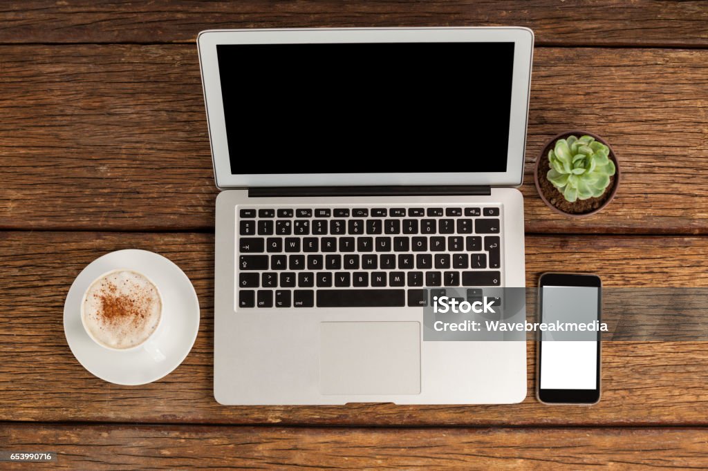 Digital tablet, laptop and smartphone with cup of coffee Digital tablet, laptop and smartphone with cup of coffee on wooden table Brown Stock Photo