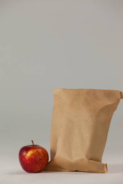 istock Brown paper lunch bag with red apple 653997302