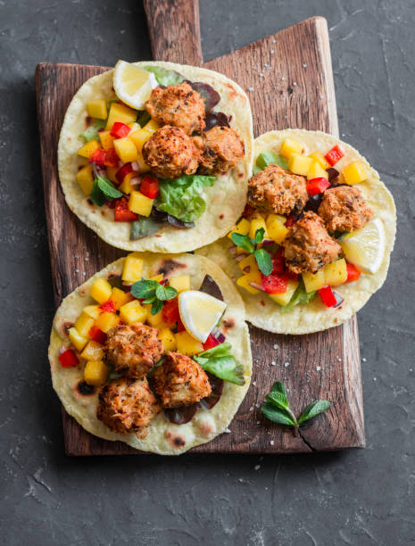 Fish tacos with mango salsa on a wooden cutting board, top view. Delicious appetizer or snack