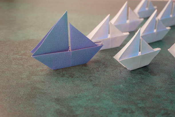 barche a vela in carta origami, concetto di leadership business, tonizzazione - guida turistica professione foto e immagini stock