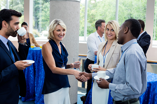 Business executives interacting with each other while having coffee at conference center