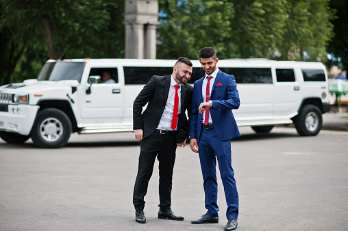 Kyiv, Ukraine - June 25, 2015: Two stylish arabic businessman mans in tuxedo background white Hummer limousine