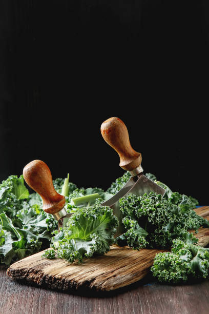 Fresh chopped Kale Italian salad on old wooden board with a knif Fresh chopped Kale Italian salad on old wooden board with a knife. Dark background knif stock pictures, royalty-free photos & images