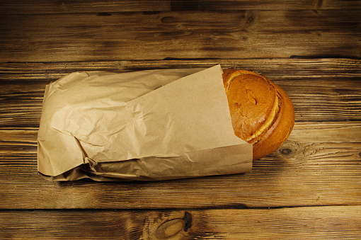Bread packed in paper on wooden table