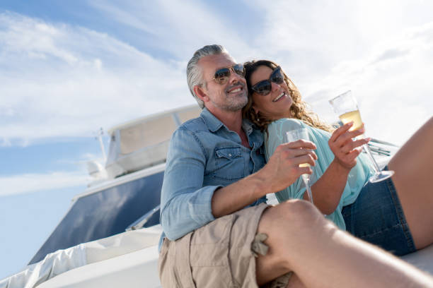 Couple sailing on a yacht Portrait of a loving couple sailing on a yacht and drinking champagne while enjoying the summer sailing couple stock pictures, royalty-free photos & images